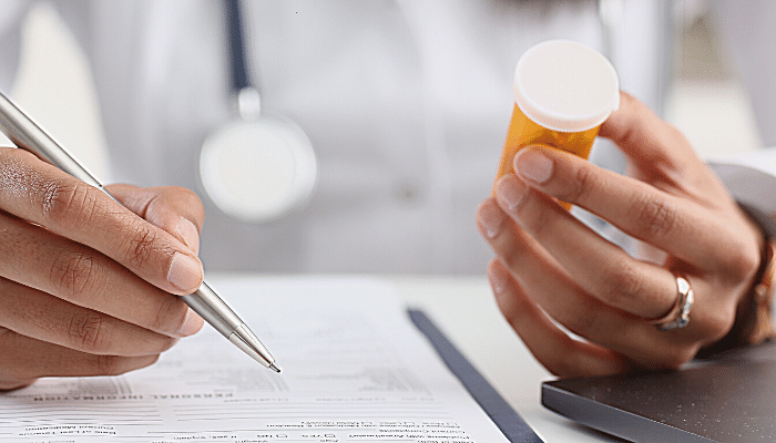 Doctor holding a pill bottle and writing