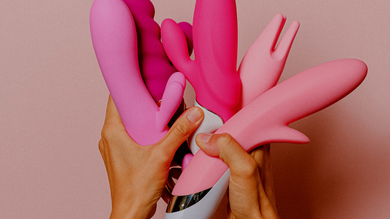 Hands holding a variety of vibrators and dildos