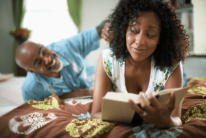 Woman in bed reading with her partner