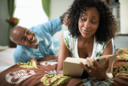 Woman in bed reading with her partner