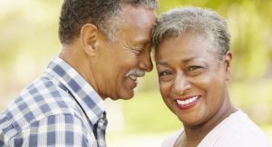 An older couple resting their heads together smiling