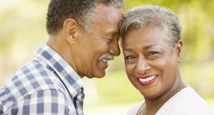 An older couple resting their heads together smiling