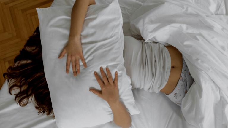Woman in bed with a pillow over her face