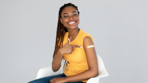 A woman points to a bandage on her arm where she was vaccinated
