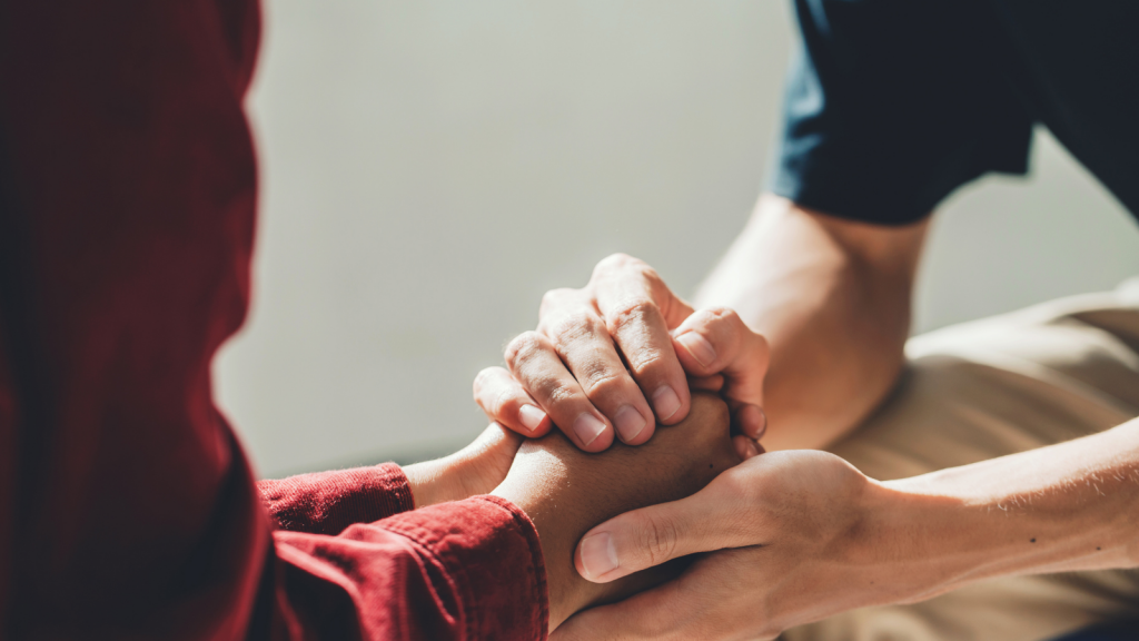 Two people clasping hands in support