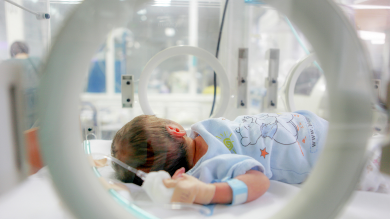 An infant is in an incubator in the NICU