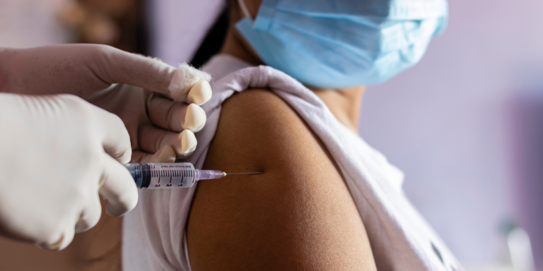 A young person wearing a mask gets vaccinated