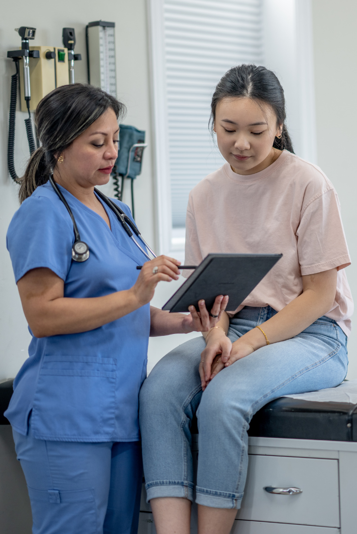 A health care provider talks to a young patient at a clinic