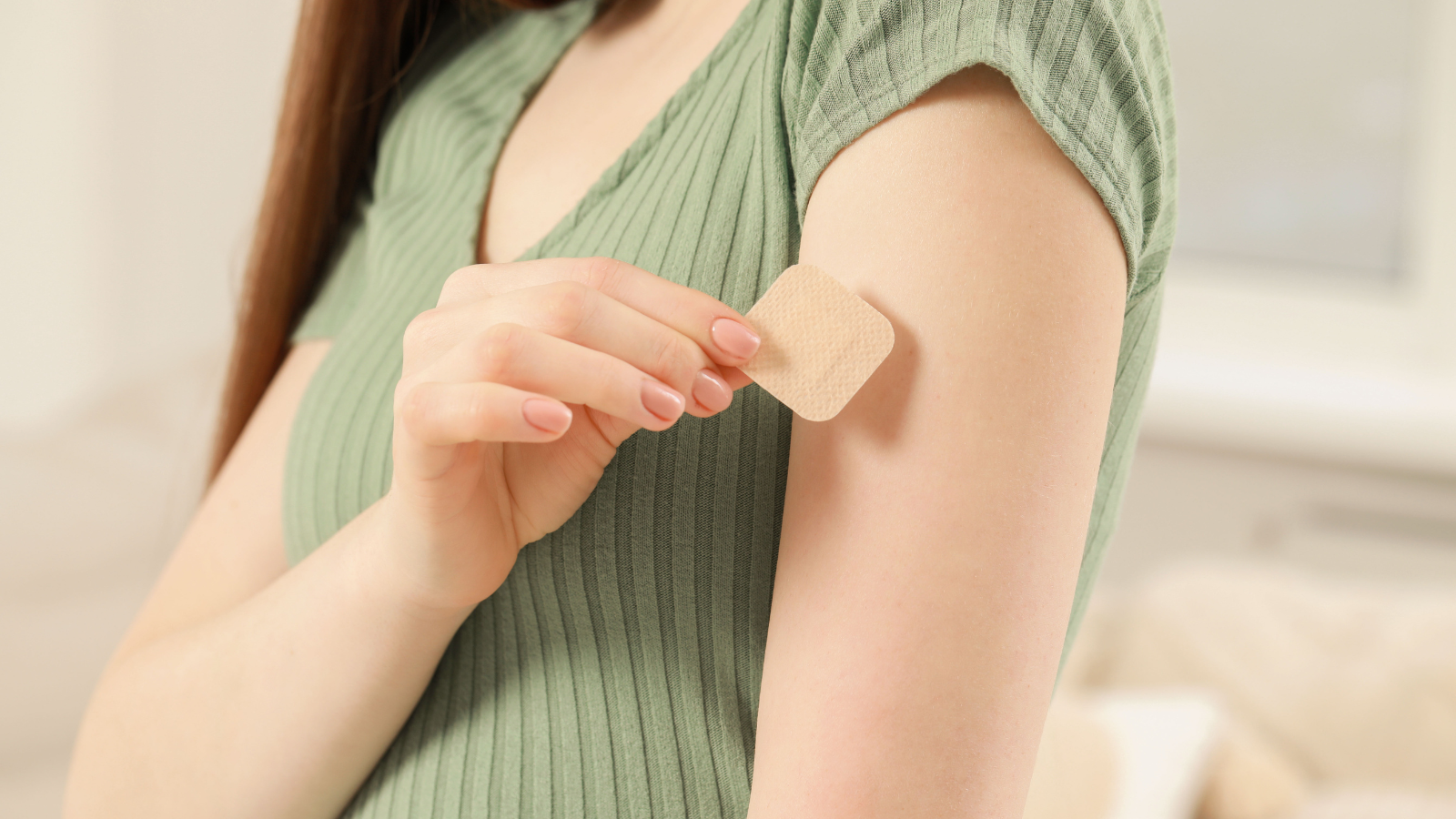 A person applies a contraceptive patch on the arm