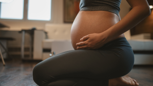 A pregnant person kneels on the floor