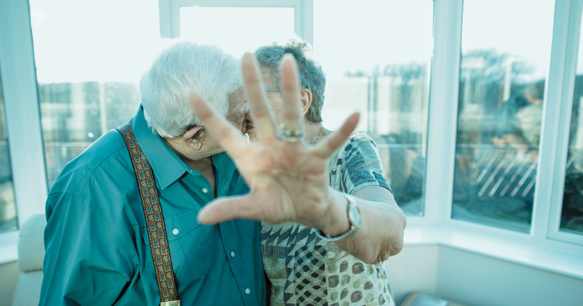 An older couple kisses while holding up a hand—STIs in older adults